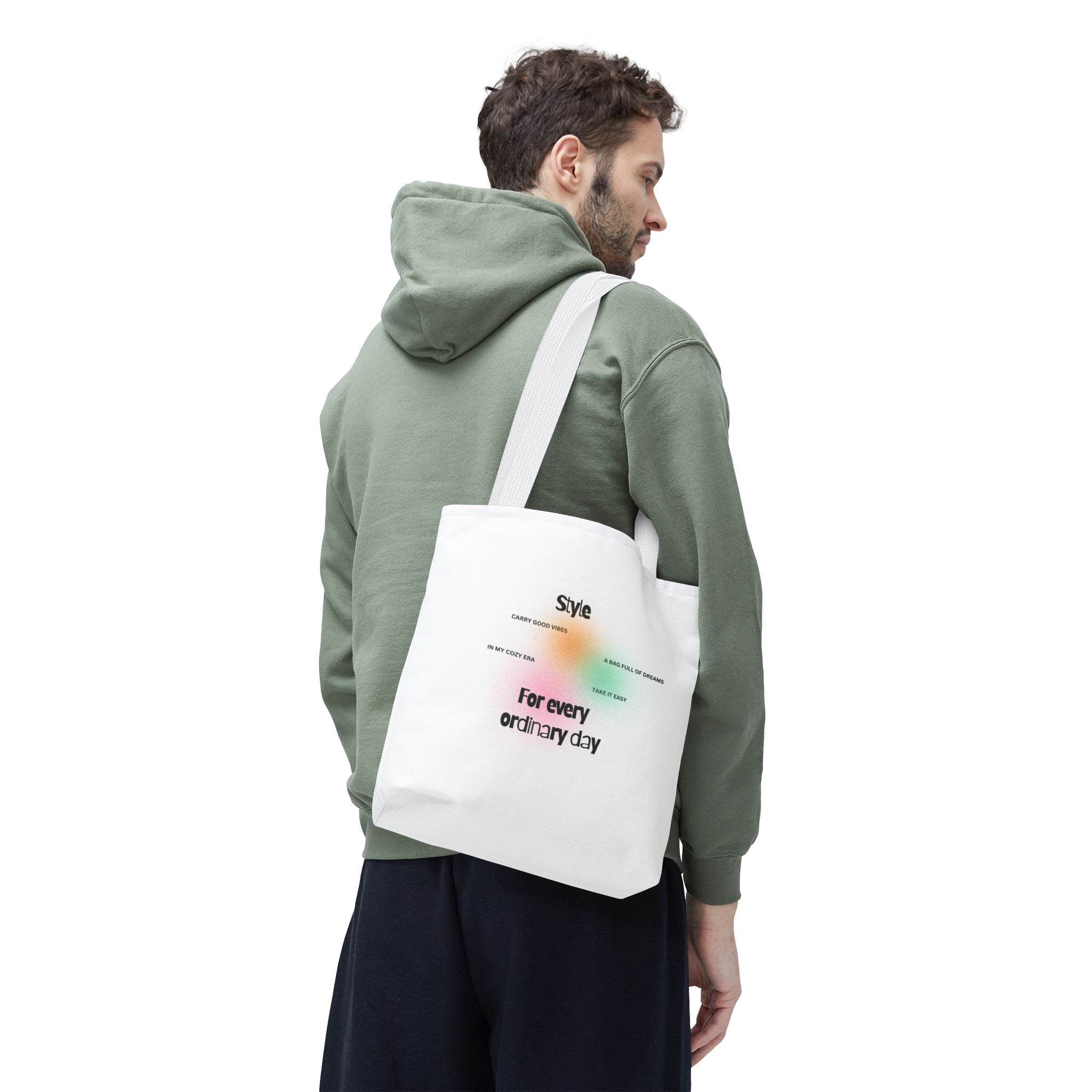 Man wearing a green hoodie with a white tote bag on a white background