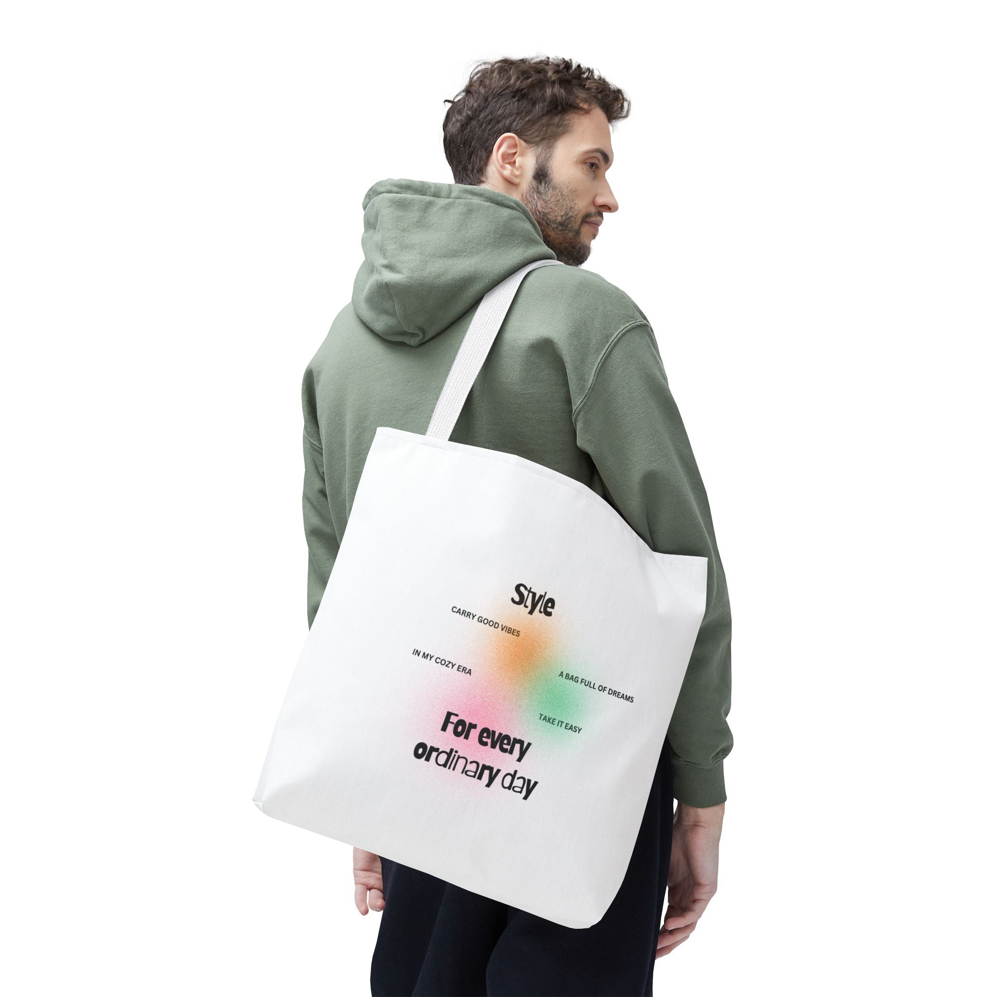 Man wearing a green hoodie with a white tote bag featuring text and graphics.