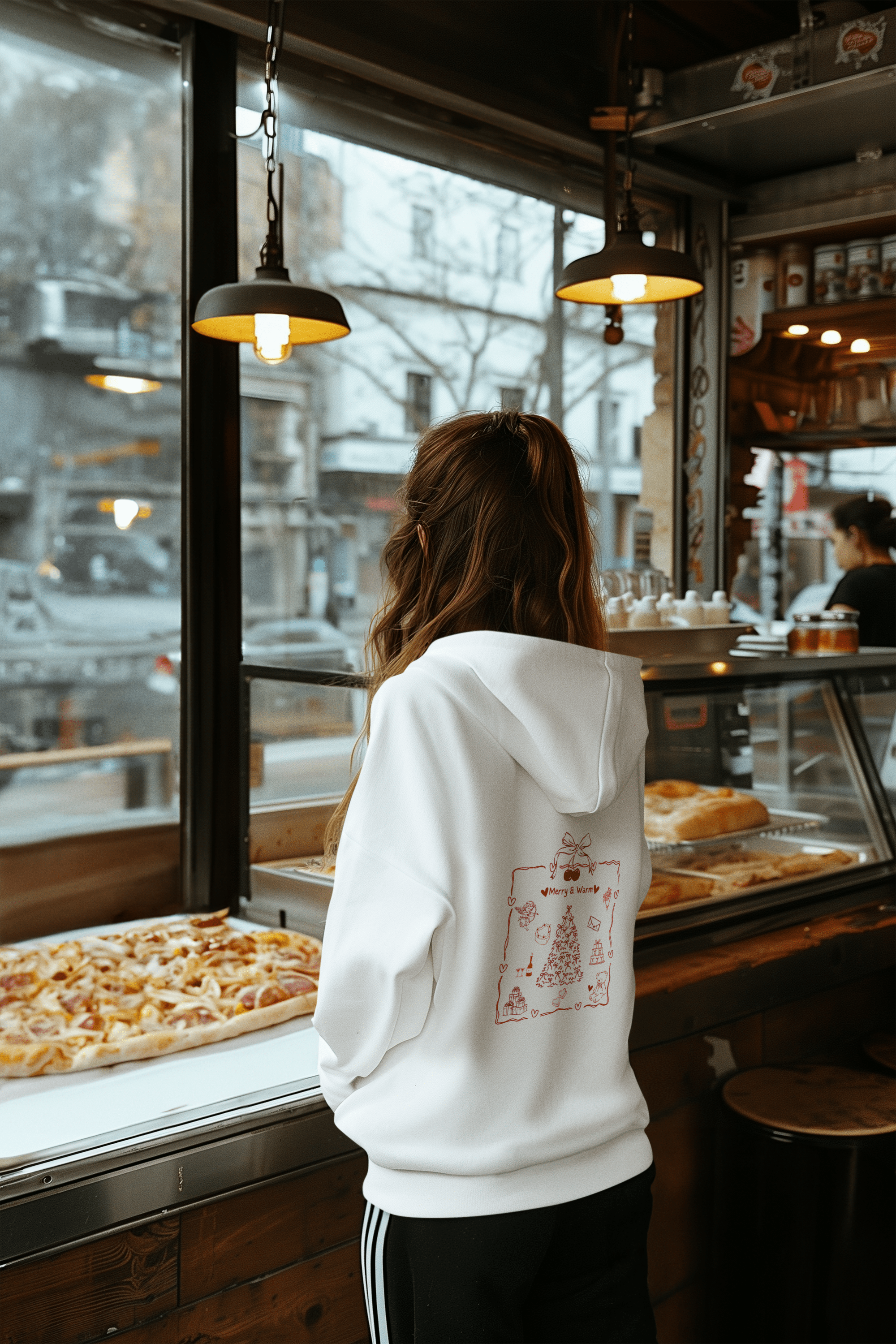 White woman hoodie featuring a festive red Christmas-themed design on the back with ‘Merry & Warm’ text. 